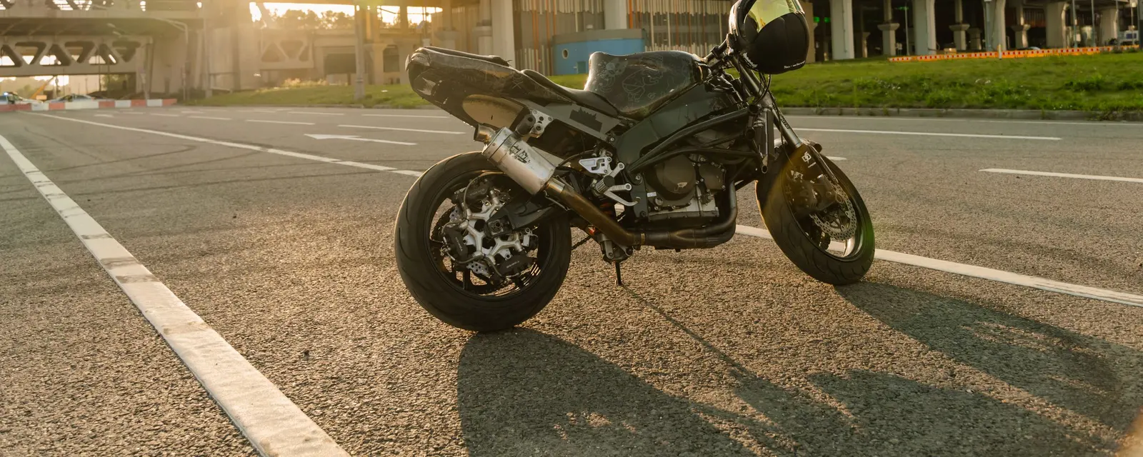 A motorbike parked on an empty road in low golden light