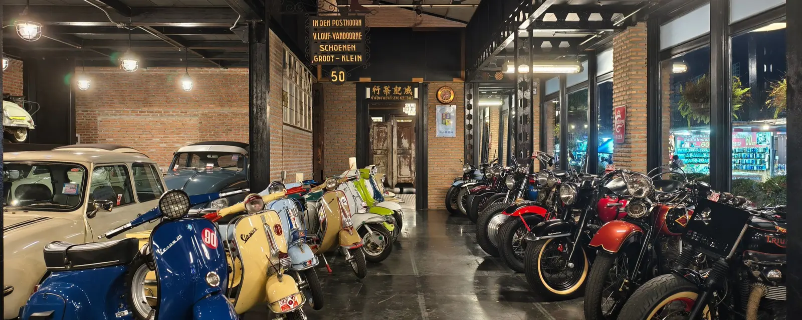 Classic motorbikes and scooters lined up inside a warm brick storage hall