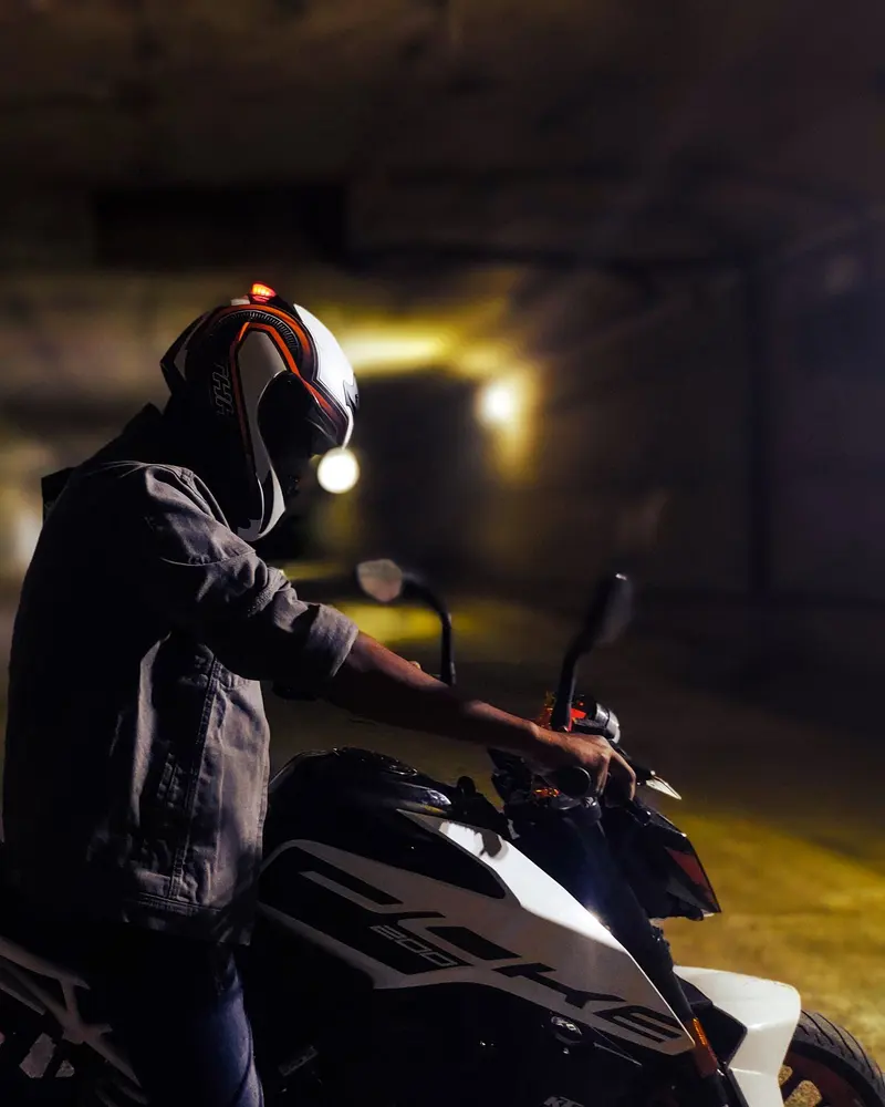 A rider in a full-face helmet waits at night under street light
